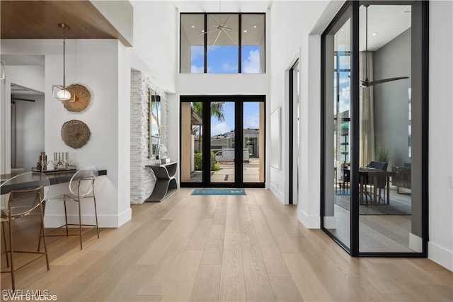 foyer with french doors, a towering ceiling, and light hardwood / wood-style floors