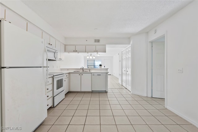 kitchen with white appliances, white cabinets, sink, light tile patterned flooring, and kitchen peninsula