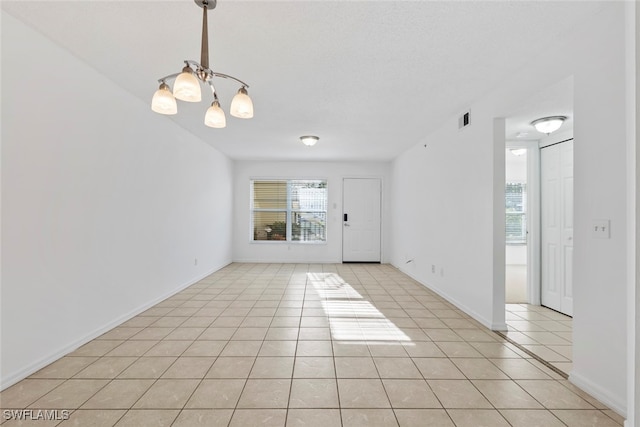 tiled empty room with an inviting chandelier