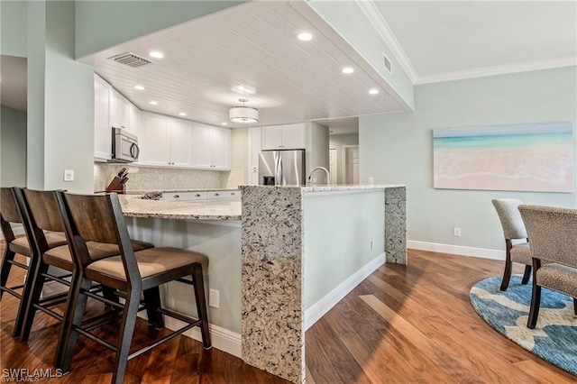 kitchen featuring visible vents, backsplash, wood finished floors, appliances with stainless steel finishes, and light stone countertops