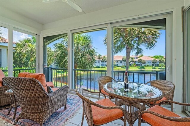 sunroom featuring a water view and ceiling fan