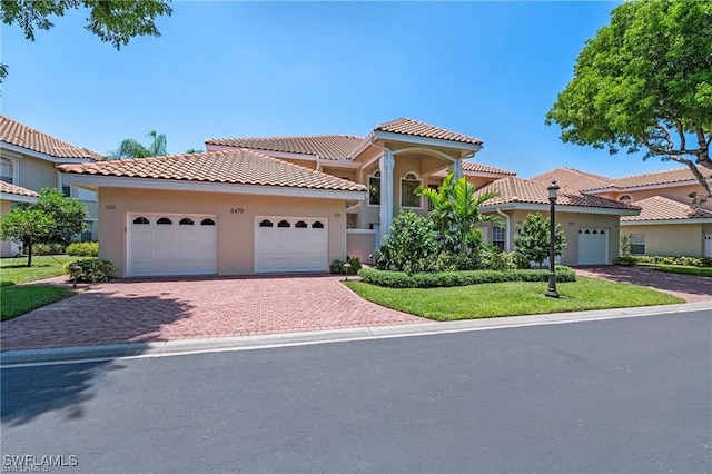 mediterranean / spanish-style house featuring stucco siding, a tiled roof, decorative driveway, and a garage