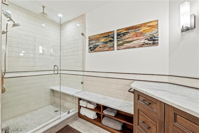 bathroom featuring vanity, a shower stall, tile walls, and wainscoting