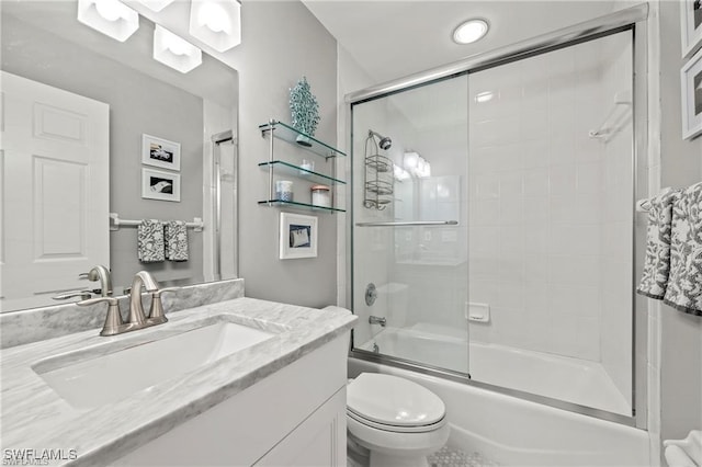 full bath with vanity, toilet, and shower / bath combination with glass door