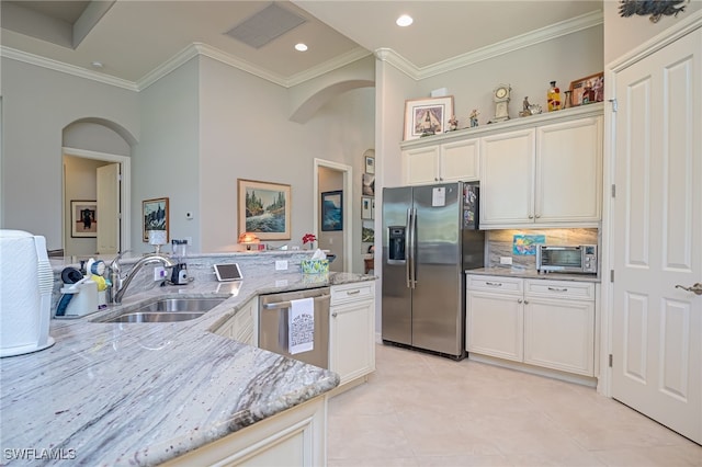 kitchen featuring appliances with stainless steel finishes, a towering ceiling, light stone counters, crown molding, and sink