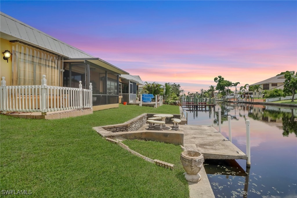 view of dock with a water view and a yard