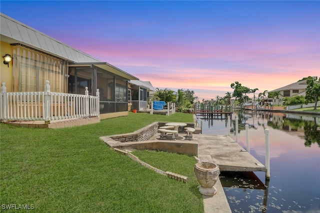 view of dock with a water view and a yard