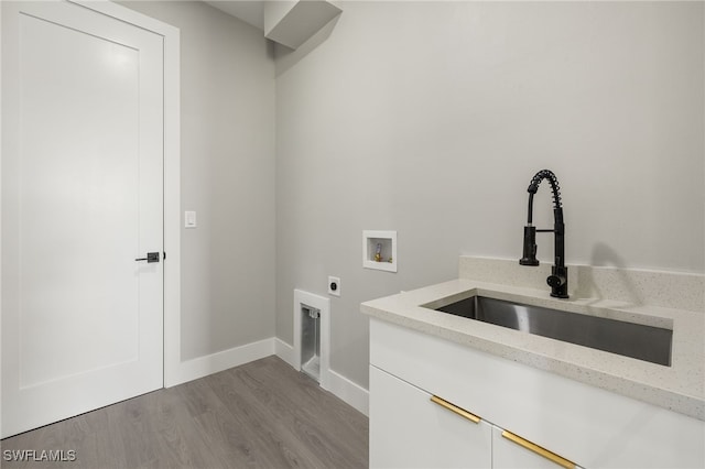 laundry room with cabinets, washer hookup, electric dryer hookup, sink, and light hardwood / wood-style flooring