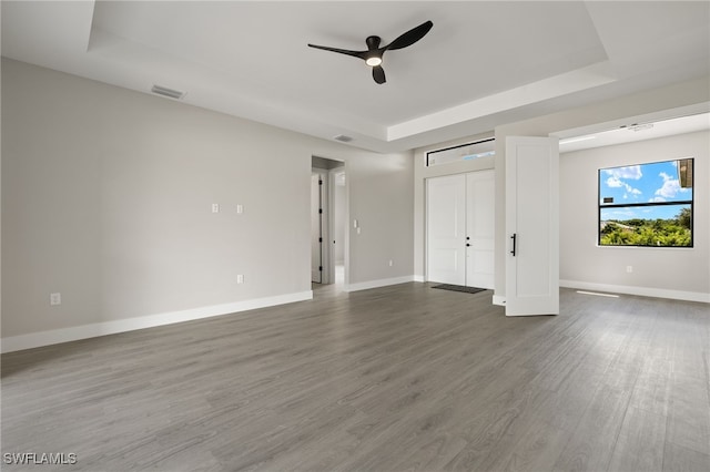 unfurnished bedroom featuring a raised ceiling, ceiling fan, and wood-type flooring