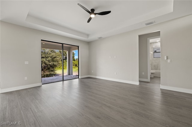 unfurnished room with ceiling fan, dark hardwood / wood-style flooring, and a raised ceiling