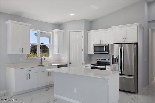 kitchen featuring stainless steel appliances, vaulted ceiling, sink, a center island, and white cabinetry