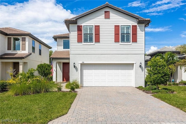 view of front of house with decorative driveway, a tiled roof, an attached garage, and stucco siding