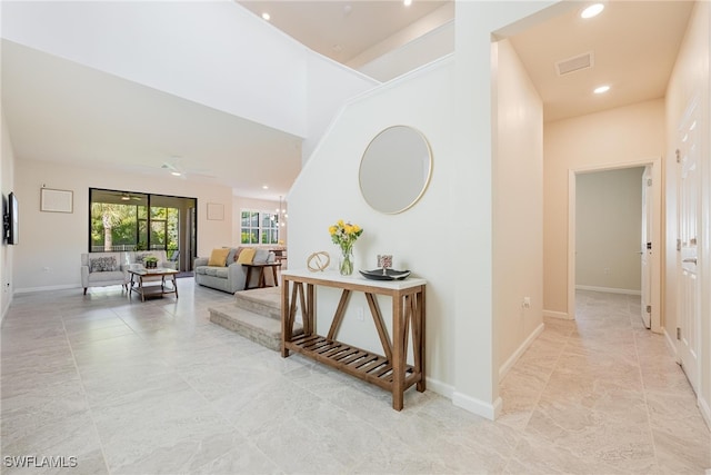 corridor featuring recessed lighting, visible vents, a towering ceiling, and baseboards