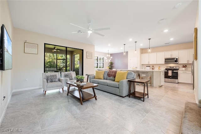 living area featuring recessed lighting, ceiling fan with notable chandelier, and baseboards