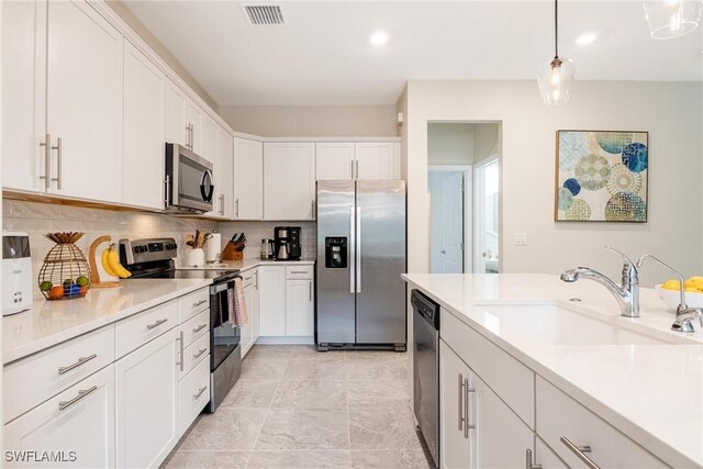 kitchen with visible vents, a sink, stainless steel appliances, white cabinets, and light countertops