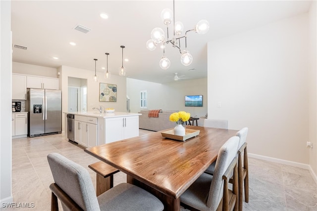 dining space featuring ceiling fan with notable chandelier and sink