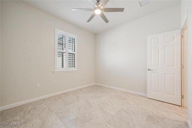 spare room featuring visible vents, a ceiling fan, and baseboards