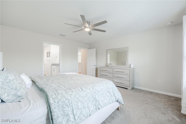 bedroom with ceiling fan, light colored carpet, and ensuite bath