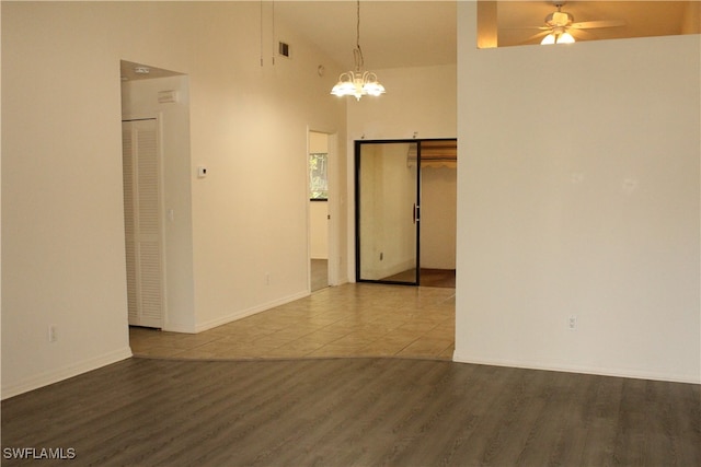 spare room with ceiling fan with notable chandelier and tile patterned floors