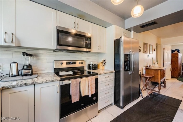 kitchen with stainless steel appliances, light stone countertops, decorative backsplash, white cabinets, and light tile patterned flooring