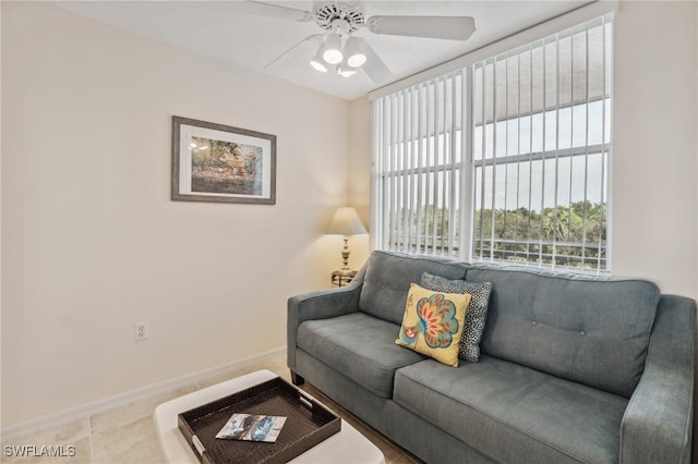 tiled living area with baseboards and ceiling fan