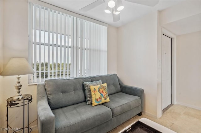 living area with baseboards and a ceiling fan