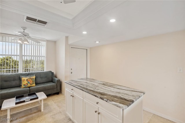 kitchen with visible vents, ceiling fan, light stone countertops, open floor plan, and white cabinetry