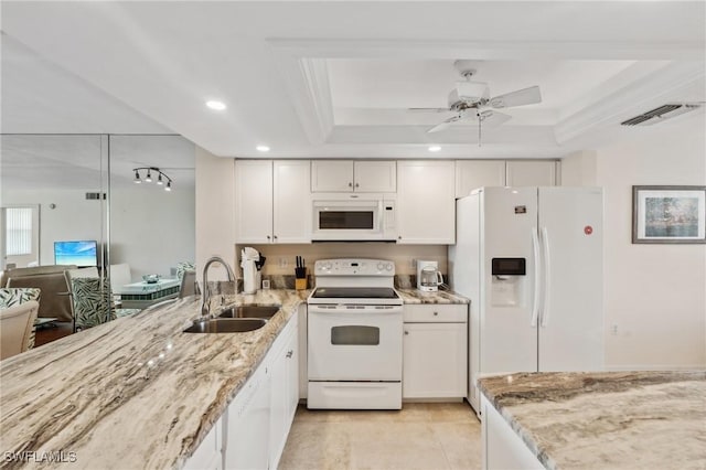 kitchen featuring visible vents, a sink, a tray ceiling, white appliances, and light stone countertops