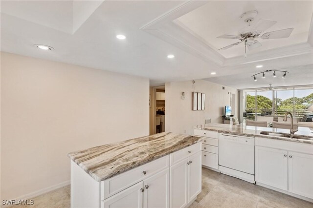 kitchen featuring a sink, light stone counters, a kitchen island, white dishwasher, and a raised ceiling