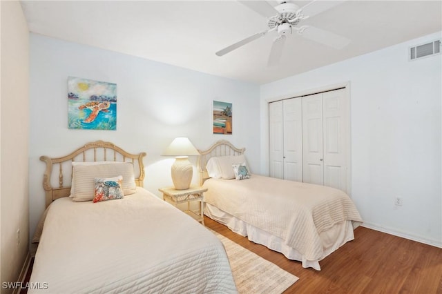 bedroom with wood finished floors, visible vents, a closet, and ceiling fan