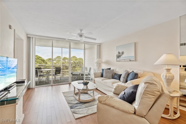 living room featuring ceiling fan, floor to ceiling windows, and wood-type flooring