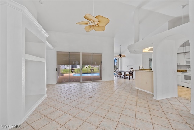 tiled empty room with ceiling fan and high vaulted ceiling