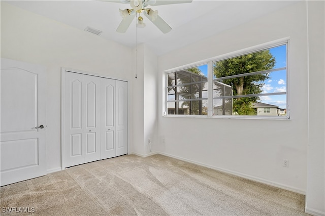 unfurnished bedroom featuring ceiling fan, a closet, and light carpet