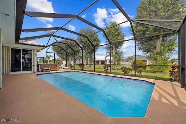 view of pool featuring glass enclosure, a lawn, and a patio