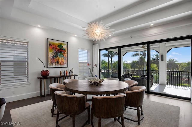 dining space featuring a raised ceiling, hardwood / wood-style flooring, and an inviting chandelier