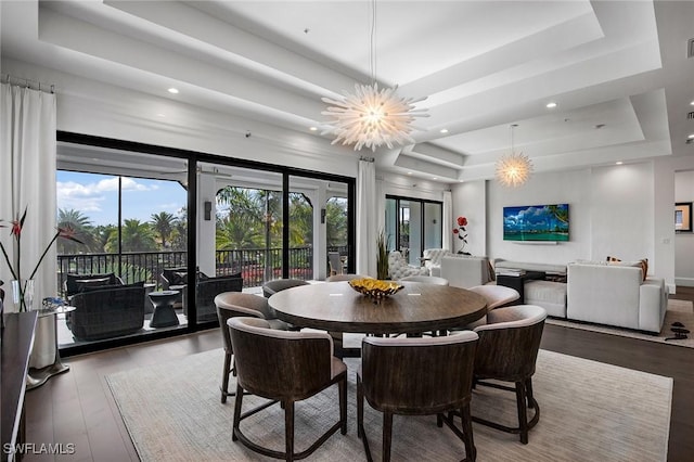 dining room featuring a tray ceiling, a chandelier, and light wood-type flooring