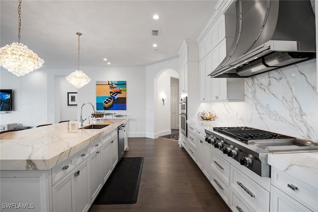 kitchen featuring ventilation hood, sink, an island with sink, appliances with stainless steel finishes, and dark hardwood / wood-style flooring