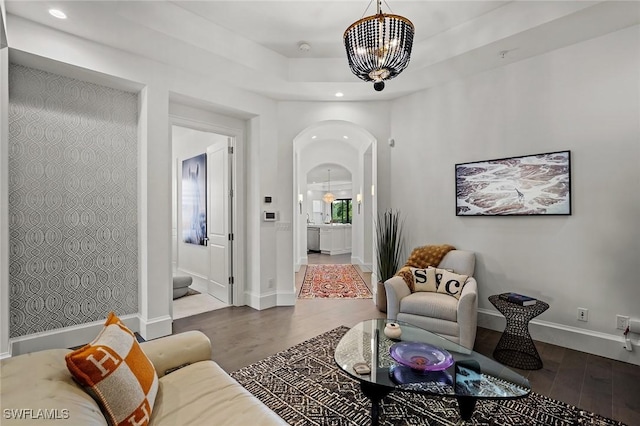 living room with hardwood / wood-style floors, a tray ceiling, and a chandelier