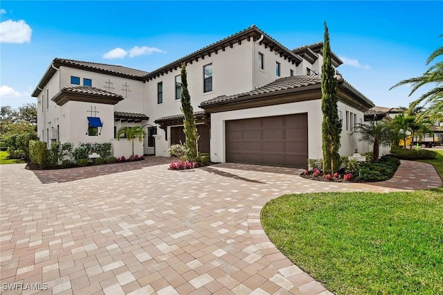 mediterranean / spanish home featuring a garage and a front lawn