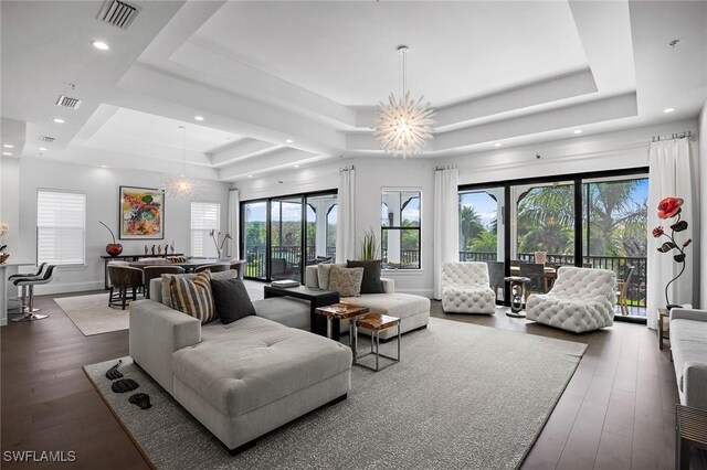 living room featuring a raised ceiling, wood-type flooring, a wealth of natural light, and a chandelier