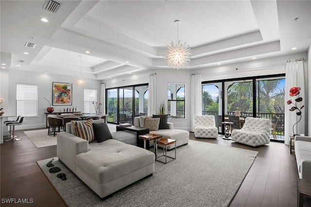 living room featuring dark hardwood / wood-style floors, a raised ceiling, and a notable chandelier