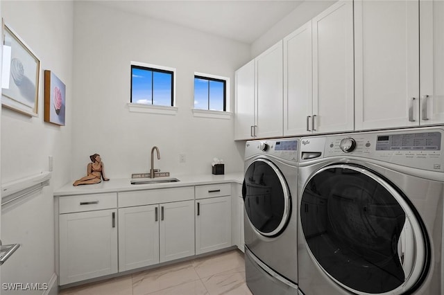 clothes washing area featuring washer and clothes dryer, sink, and cabinets