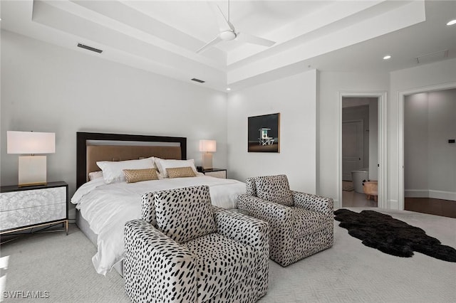 bedroom with a raised ceiling, ensuite bath, ceiling fan, and carpet