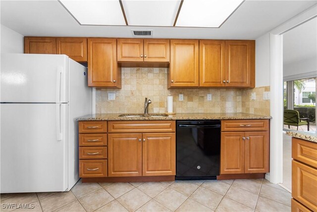 kitchen with light stone counters, dishwasher, light tile patterned floors, white fridge, and sink