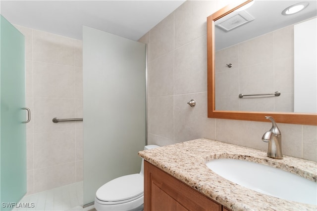 bathroom featuring tile walls, an enclosed shower, vanity, and toilet