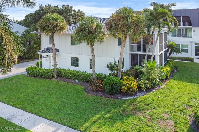 view of property exterior featuring a balcony and a lawn