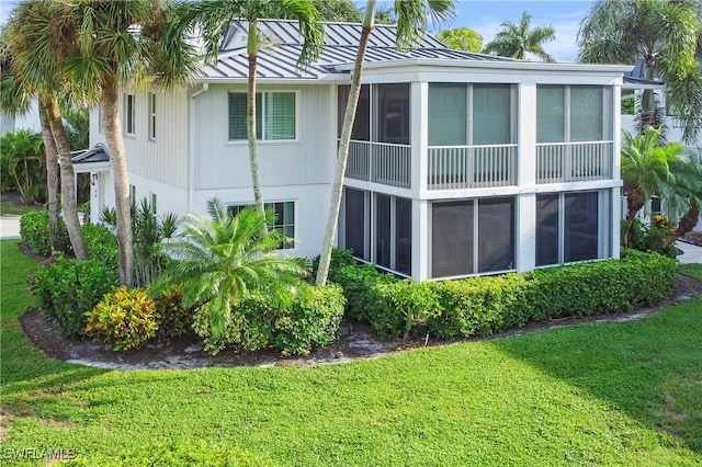 view of property exterior featuring a lawn and a sunroom