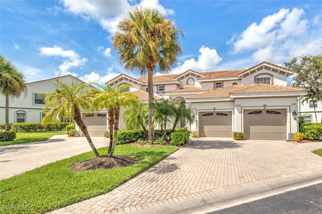 mediterranean / spanish-style home with a tile roof, decorative driveway, a garage, and stucco siding