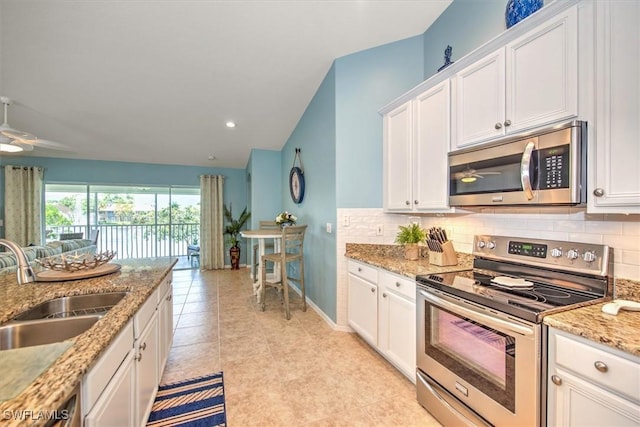 kitchen featuring ceiling fan, decorative backsplash, a sink, white cabinets, and appliances with stainless steel finishes