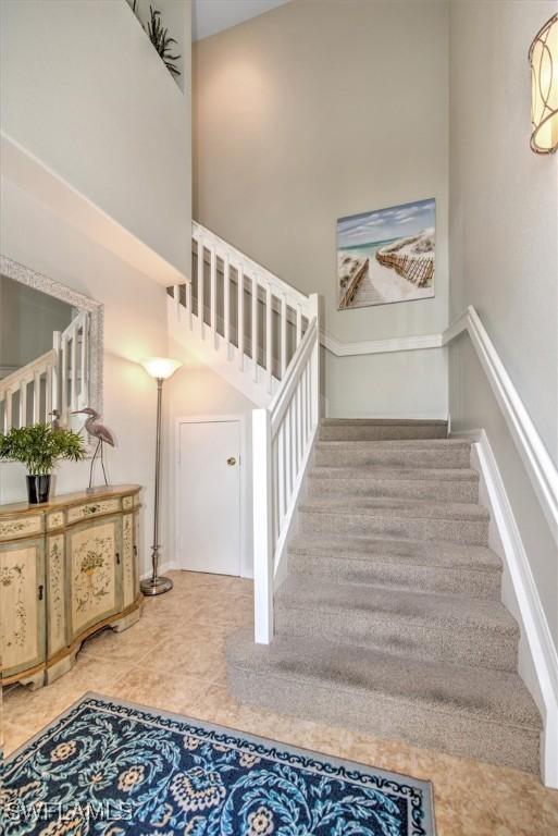 stairs with tile patterned floors and a high ceiling